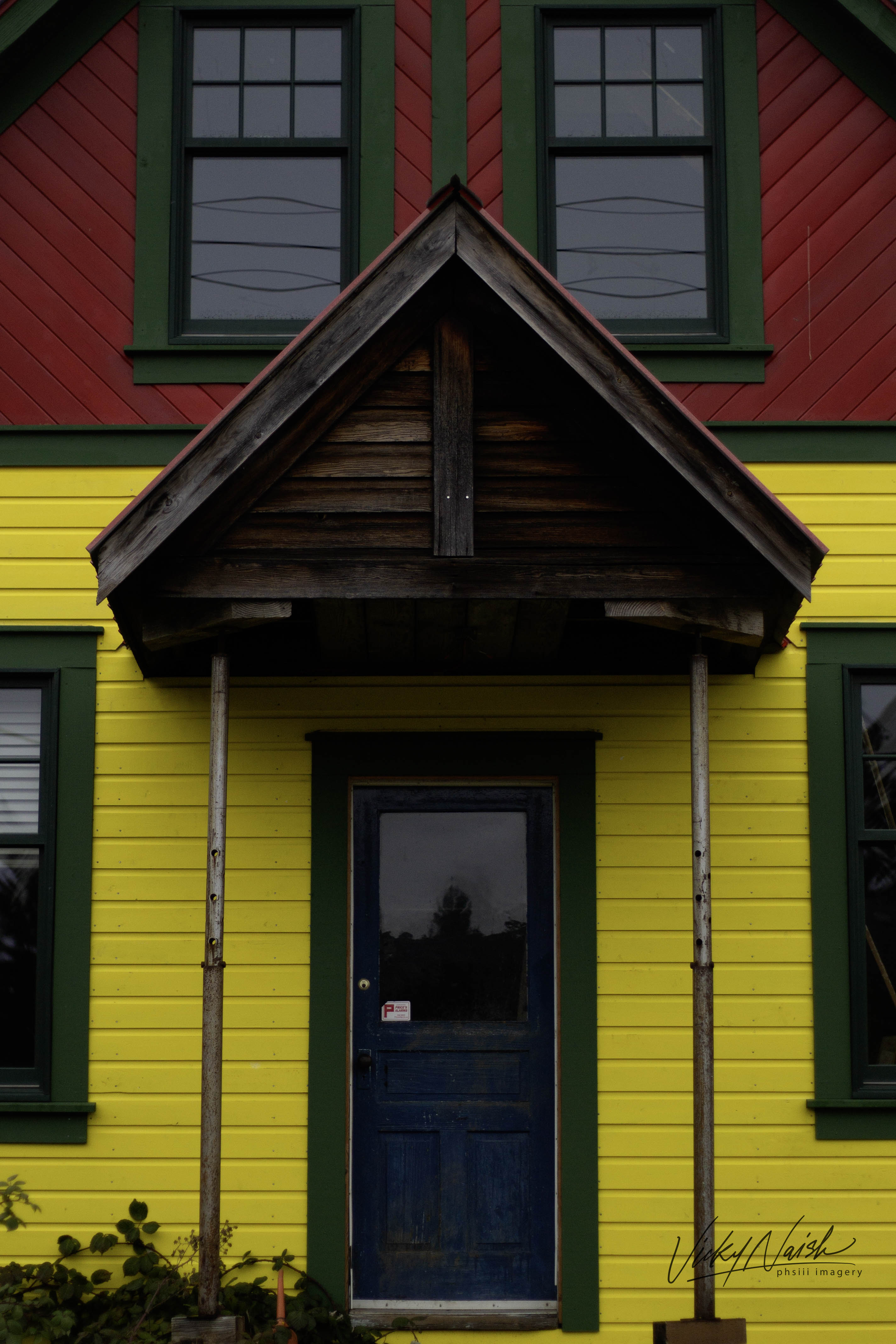 closeup of the front of a a red, yellow, green and blue wood house