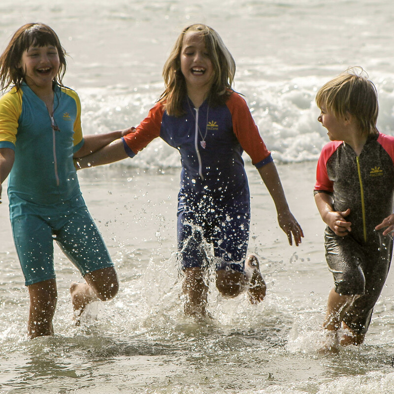 3 happy girls in sun swimsuits running out of the ocean