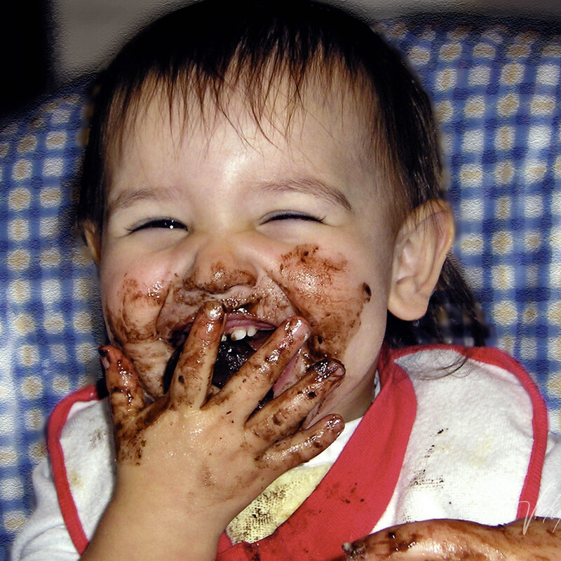 portrait of  a smiley toddler messily eating chocolate cookies